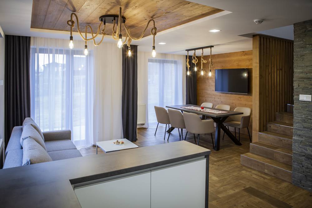 Obývacia a jedálenská časť apartmánu č. 1 s dreveným stropom a kamennou stenou